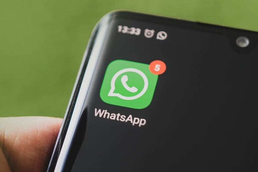 A WhatsApp ikonja, alkalmazás egy fekete okostelefon képernyőjén.