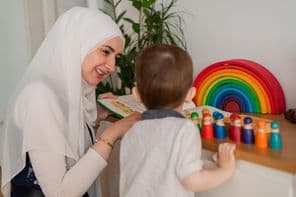 Egy muszlim tanár és egy óvodáskorú gyermek színes játékokkal játszanak