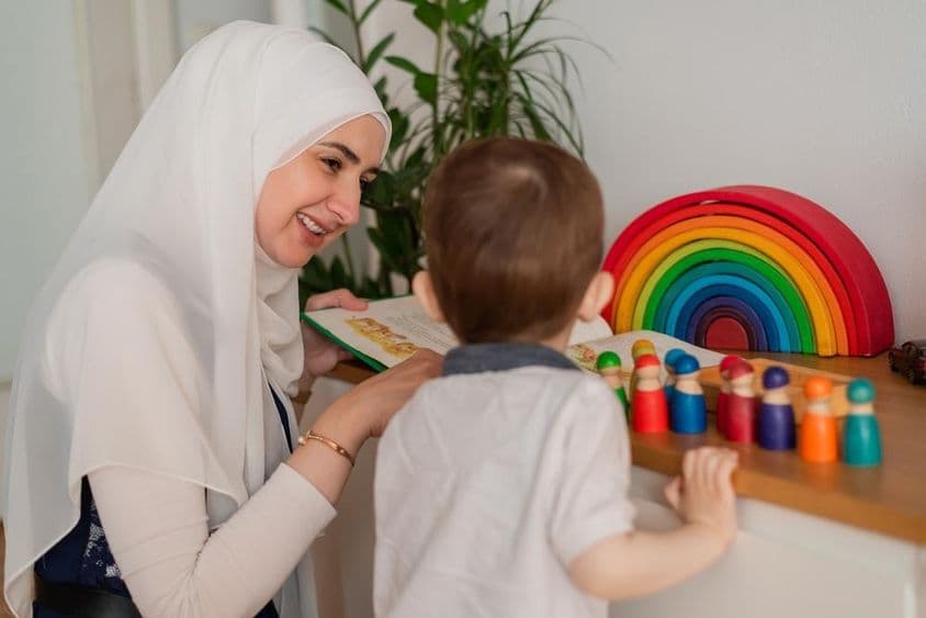 Egy muszlim tanár és egy óvodáskorú gyermek színes játékokkal játszanak