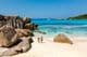 Két utazó sétál az Anse Cocos Beach puha fehér homokján Seychelle-szigeteken.