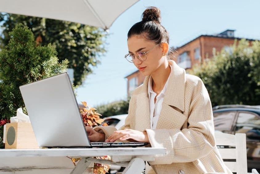 Stílusos üzletasszony szemüvegben dolgozik laptopon